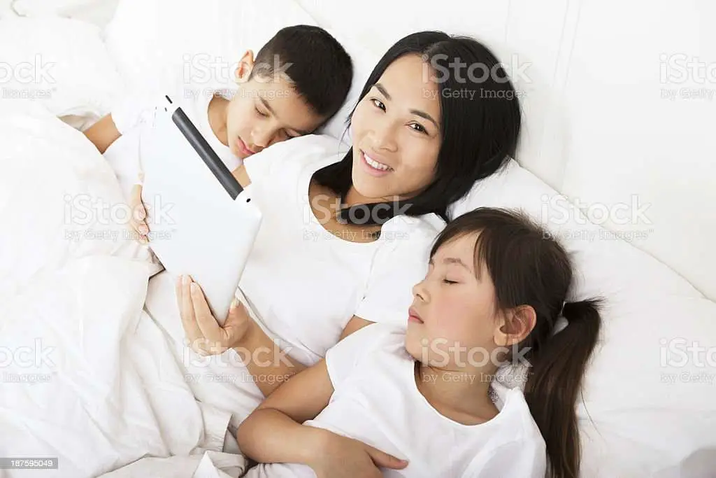 Mom Putting Kids To Sleep Using A Tablet Stock Photo ...